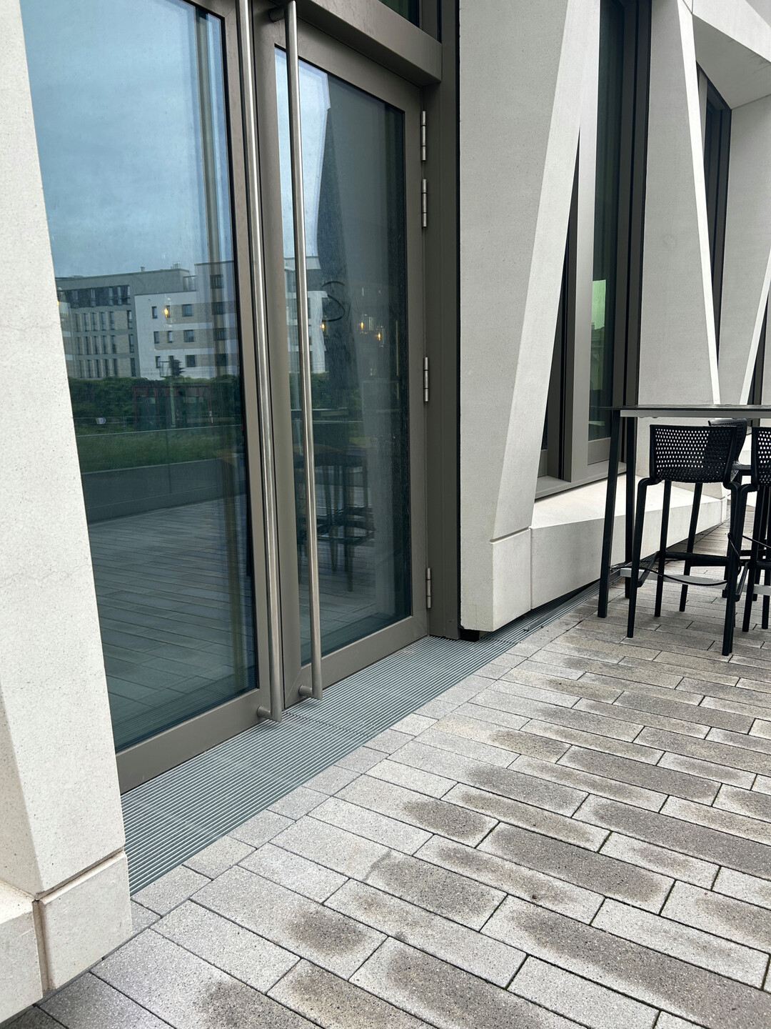 An den Gebäude-Eingängen befinden sich ACO Fassadenrinnen, die das Spritzwasser minimieren und barrierefrei sowie schwellenlos ausgebildet sind.