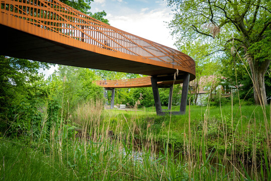 Das skulptural wirkende Geländer nimmt die tragenden Lasten der Brücke auf, die Brückenpfeiler sind lediglich Stützen.