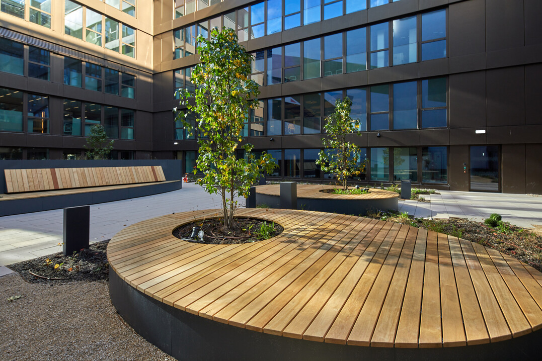 Die ovalen Sitzinseln sind aus unbehandeltem Movingui-Holz und pulverbeschichtetem Stahl.