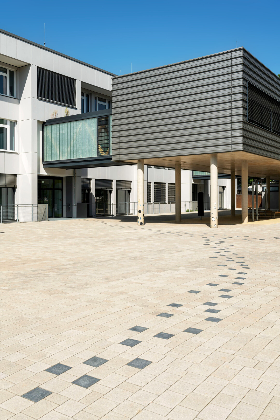 Dunkel abgesetzte Pflastersteine leiten zum Haupteingang. 