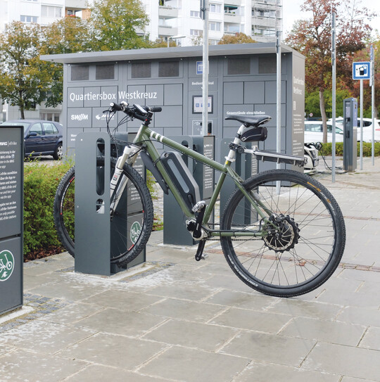 Die Abstellanlage Velo-Connector kann mehr: Sie ist Ladestation für eines oder mehrere E-Bikes, ein diebstahlsicherer Abstellort als auch ein verschließbarer Stauraum für Helm und Gepäck.