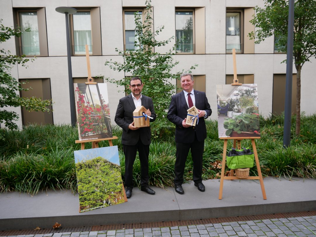 Bauminister Christian Bernreiter und Gesundheitsminister Klaus Holetschek mit den Gewinnerfotos samt Preisen des gemeinsamen Wettbewerbs „Grüner Freiraum am Haus“
