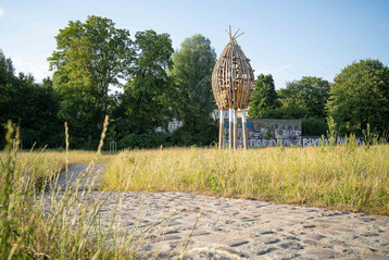Als weithin sichtbare Land Art ragt der riesige Artenschutzturm aus den Auenwiesen heraus.